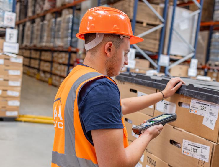 muncitor cu un aparat cititor de cod de bare prestand serviciul de picking in depozitul RARA Logistic CTP Sibiu